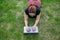 Mobile office. Top view of a freelancer woman typing a laptop while lying on the lawn. Work outdoors. Girl studying on a