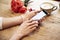 Mobile phone in beautiful woman hands. Lady using internet in cafe. Red roses flowers behind on wooden table. St. Valentine`s day