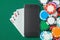 Mobile phone casino online. Mobile phone and game cards with chips on green gaming table. Gambling addiction in cracking games