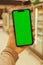 Mobile phone Chroma key on defocused frozen food fridge background. Close up of woman hand holds smart phone with green