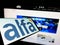 Mobile phone with logo of Mexican company Grupo Alfa on screen in front of business website.