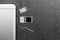 Mobile phone and open slots for nano SIM cards, micro SD drive and metal key on grey background with copy space