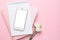 Mobile phone, white eustoma flower and notebook on pink background. Women`s business technology composition