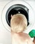 Mobile photo of blonde child hindhead in front of washing machine