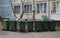 Mobile plastic green garbage containers under the Windows of a residential building
