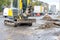 A mobile road excavator repairs sewer storm drains on a fenced carriageway of a city street