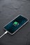 Mobile smart phone on wireless charging device on dark background. Icon battery and charging progress lighting on screen.