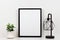 Mock up black frame against white wall with succulent plant and lamp on a white shelf