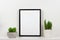 Mock up black frame against white wall with succulent plants on a white shelf