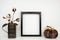 Mock up black frame with autumn cotton branch and plaid pumpkin decor on a shelf or desk