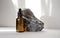 Mock-up of bottle with dropper lid, made of brown glass, against background of natural stone made of gray marble. Rays