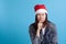 mock-up of a brooding, frowning, suspicious Asian young woman in a Santa hat isolated on a blue background