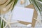 Mock up card template on white wooden background. Tropical palm leaf, summer hat, seastars and craft envelope