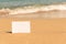 Mock up cardboard paper for text on sand beach opposite sea wave. Close-up. Copy space.