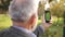 Mock up of elderly man using phone outside. Green screen. Back view of man holding phone at harm`s length. Grandpa