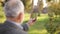 Mock up of elderly man using phone outside. Green screen. Back view of man holding phone at harm`s length. Grandpa