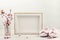 Mock up with empty picture frame, pink tender spring flowers and small baby girl shoes