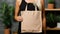 Mock-up of empty reusable rectangular canvas bag in hands of woman. Eco-friendly shopping bag made of natural material.