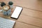 Mock up on Mobile phone screen and hot art cappuccino coffee beside wireless keyboard on a wooden table