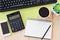 Mock up of office table desk workspace with blank notebook, smart phone, calculator, computer keyboard and coffee