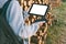 Mock-up of a tablet in the hands of a girl with a power bank charger. Against the background of folded timber, round wood