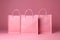 Mock up of three empty pastel pink paper shopping bags isolated on pink background, no brand, cosmetic, fashion, beauty product