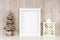 Mock up white frame with Christmas tree and lantern decor on a shelf against a rustic gray wood wall