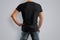 Mockup black T-shirt on a back strong man in blue jeans.