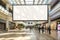 Mockup of a blank, empty billboard, facing the camera, large and busy shopping mall hall, blurred moving people