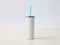 Mockup of a blank white slender tumbler with a straw and a grey background.