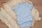Mockup of blue baby bodysuit on wood background. Blank baby clothes template mock up. Flat lay styled stock photo