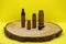Mockup of brown glass vials with dropper lid on wooden board and on yellow background. Empty glass bottles of different sizes