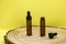Mockup of brown glass vials with dropper lid on wooden board and on yellow background. Two empty glass bottles and pipette.