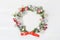 Mockup of Christmas Wreath Made of Naturalistic Looking Pine Branches Decorated with Red Berries. Flat lay on a white wooden backg