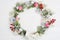 Mockup of Christmas Wreath Made of Naturalistic Looking Pine Branches Decorated with Red Berries. Flat lay on a white wooden backg