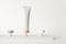 Mockup cosmetic tube stand on pedestal on white background, front view. Skin care concept. Podium with moisturizer