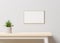 Mockup of a cozy room with white wall, wooden table, empty picture frame and a vase, 3d rendering. Template and background of a
