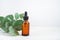 mockup glass bottle Essential oil or serum cosmetics with eucalyptus branches on textured white background