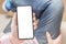 Mockup image blank white screen cell phone. Man hand holding texting using mobile on sofa at home. Empty space for advertise text