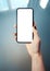 Mockup image of woman`s hand holding thin bezels mobile phone with blank screen in glossy and blurry corporate environment - Imag