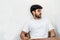 Mockup image of a young bearded man doing a pose while wearing white blank shirt