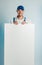 Mockup image of a young smilling worker holding empty white banner. White or blue background. Bussines concept