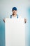Mockup image of a young smilling worker holding empty white banner. White or blue background. Bussines concept