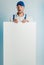 Mockup image of a young surprised worker holding empty white banner. White or blue background. Bussines concept