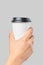 Mockup of men`s hand holding white paper large size cup with black cover