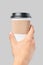 Mockup of men`s hand holding white paper large size cup with black cover