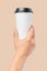 Mockup of men`s hand holding white paper large size cup with black cover