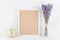 Mockup of picture frame decorated lavender flowers in vase on white working desk with clean space for text and design your bloggin