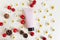 Mockup of pink squeezed cosmetic tube with black cap, camomiles, cherry berries and fir cones on ivory background. Natural organic
