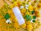 Mockup of transparent bottle of intimate lubricant gel, yellow dandelions and wild flowers on textured bright orange background.